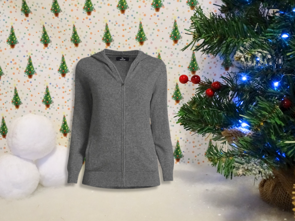 A grey zip-up hoodie is displayed in a festive scene with a Christmas tree decorated with lights, large snowballs, and a background of small green trees—perfect for holiday décor or gift ideas for adults 2022.