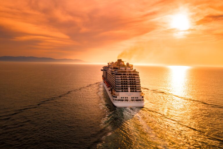 A large cruise ship sails across calm ocean waters at sunset, inspiring dreams of adventure and relaxation—the perfect scene to start thinking about six tips for planning an affordable family holiday.