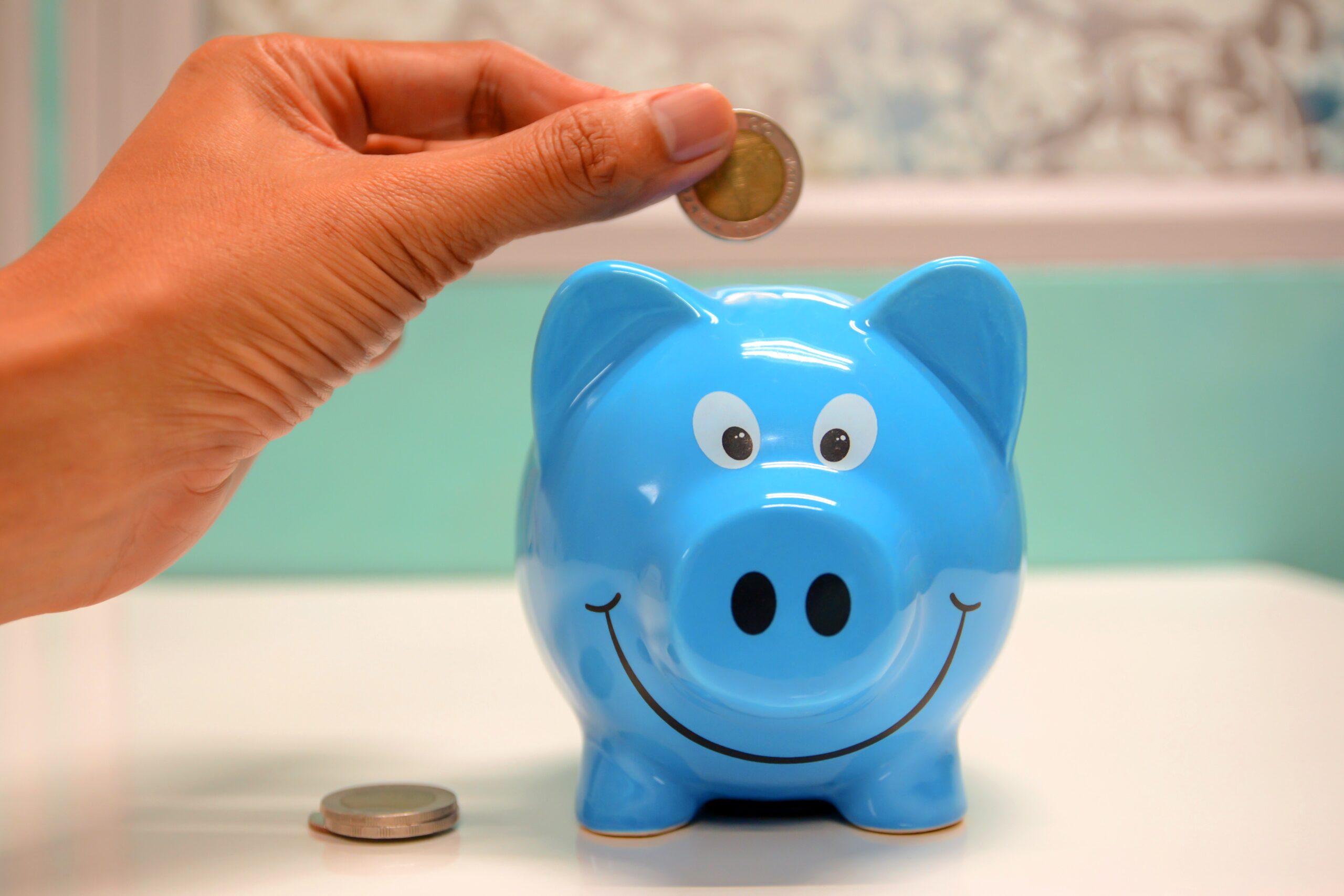 someone putting money in a blue piggy bank