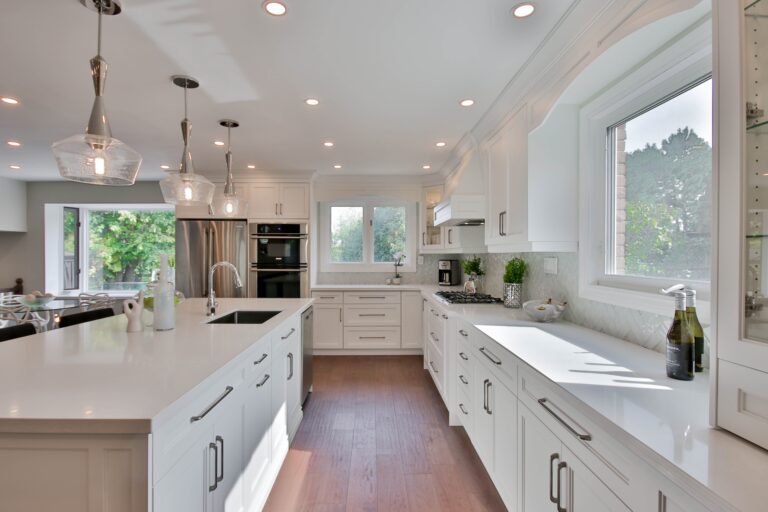 A white kitchen featuring a ktichen island, cooker and sink