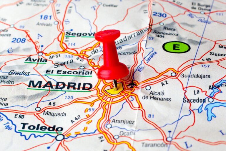 a red note pin stuck in a map of Spain. The pin is stuck in the location of Madrid