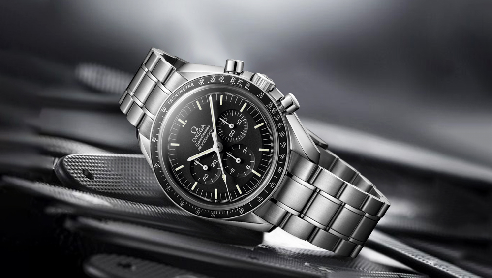A stainless steel Omega Speedmaster chronograph watch with a black dial and tachymeter bezel, elegantly displayed at an angle against a blurred, metallic background—a timeless choice for those who appreciate fine watches.