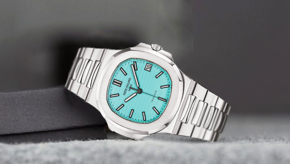 A silver wristwatch from our exclusive watches collection features a turquoise blue face, black hour markers, and a metal link strap, resting elegantly on a soft grey surface against a blurred dark background.