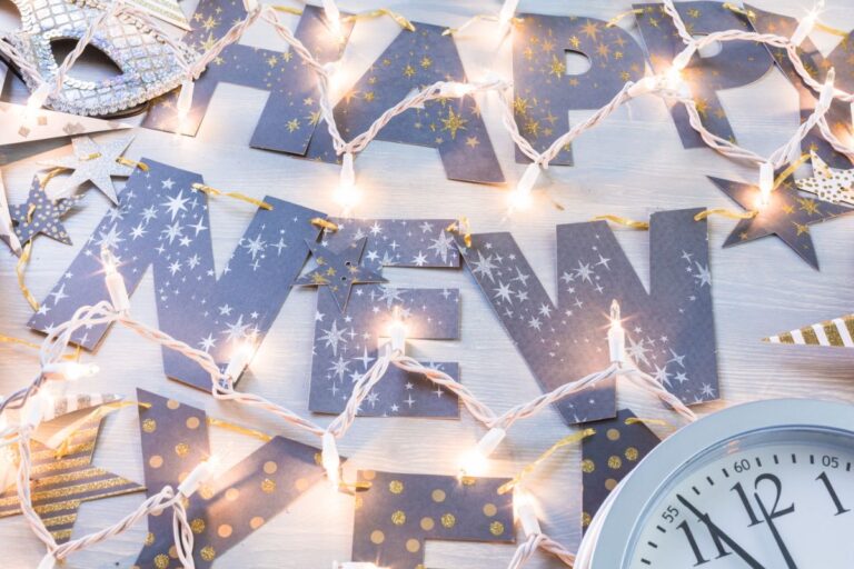 Blue and gold "Happy New Year" letters decorated with stars and fairy lights, with a partial clock showing almost midnight in the bottom right corner capture the festive spirit of New Year's Eve in Liverpool. Festive decorations create a celebratory atmosphere.