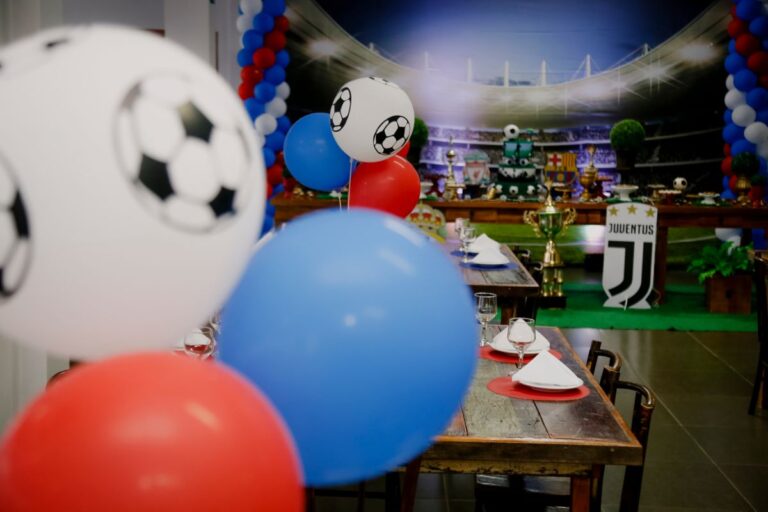 Colourful football-themed party with red, blue, and white balloons featuring football designs, decorated tables, and a Juventus logo backdrop resembling a stadium—a festive setting perfect for celebrating wins or brainstorming new side hustles.